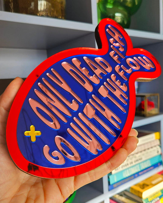 Rood-blauw visvormig spiegel acrylaat wanddecoratie met "Only dead fish go with the flow" tekst.