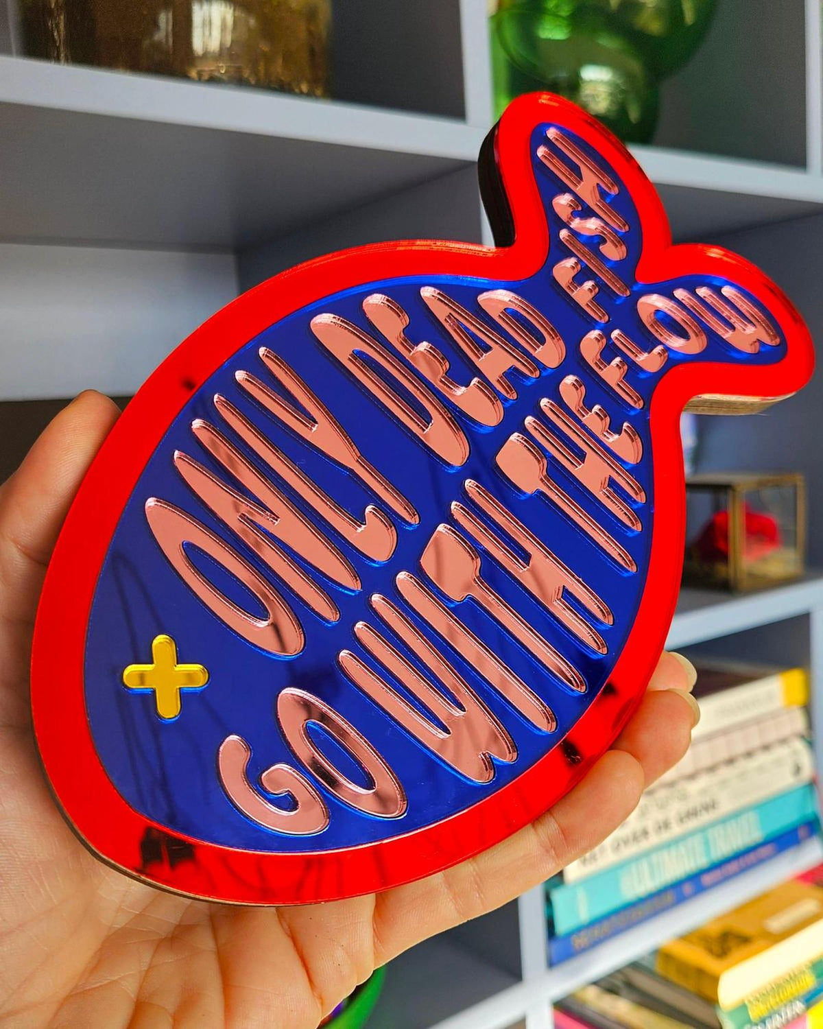 Rood-blauw visvormig spiegel acrylaat wanddecoratie met "Only dead fish go with the flow" tekst.