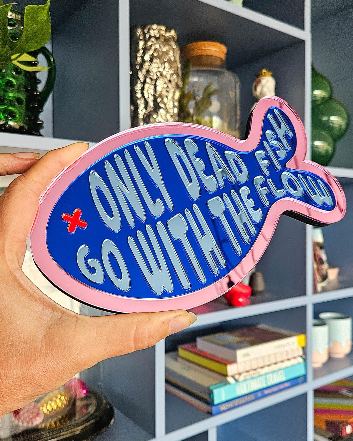 Roze en blauw visvormig spiegel acrylaat wanddecoratie met de tekst "Only dead fish go with the flow".