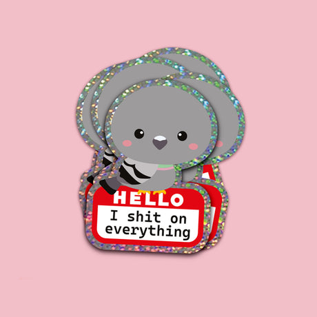 Grijze duif glittersticker met "HELLO I shit on everything" naamplaatje op roze achtergrond.