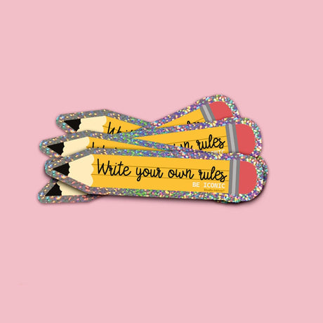 Holografische glitter sticker in de vorm van een geel potlood met de tekst Write your own rules.