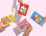Vier handen houden vier vintage kerstkaarten vast met grappige illustraties en teksten.