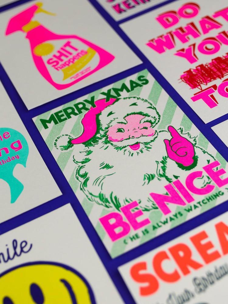 Riso kerstkaart met kerstboom, strikjes en hertjes in neon roze en groen op stevig A6 papier.
