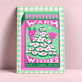 A6 Riso kerstkaart met neonroze en groene illustratie van een kerstboom, hertjes en tekst Warm Wishes op stevig papier.