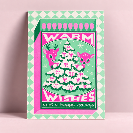 A6 Riso kerstkaart met neonroze en groene illustratie van een kerstboom, hertjes en tekst Warm Wishes op stevig papier.