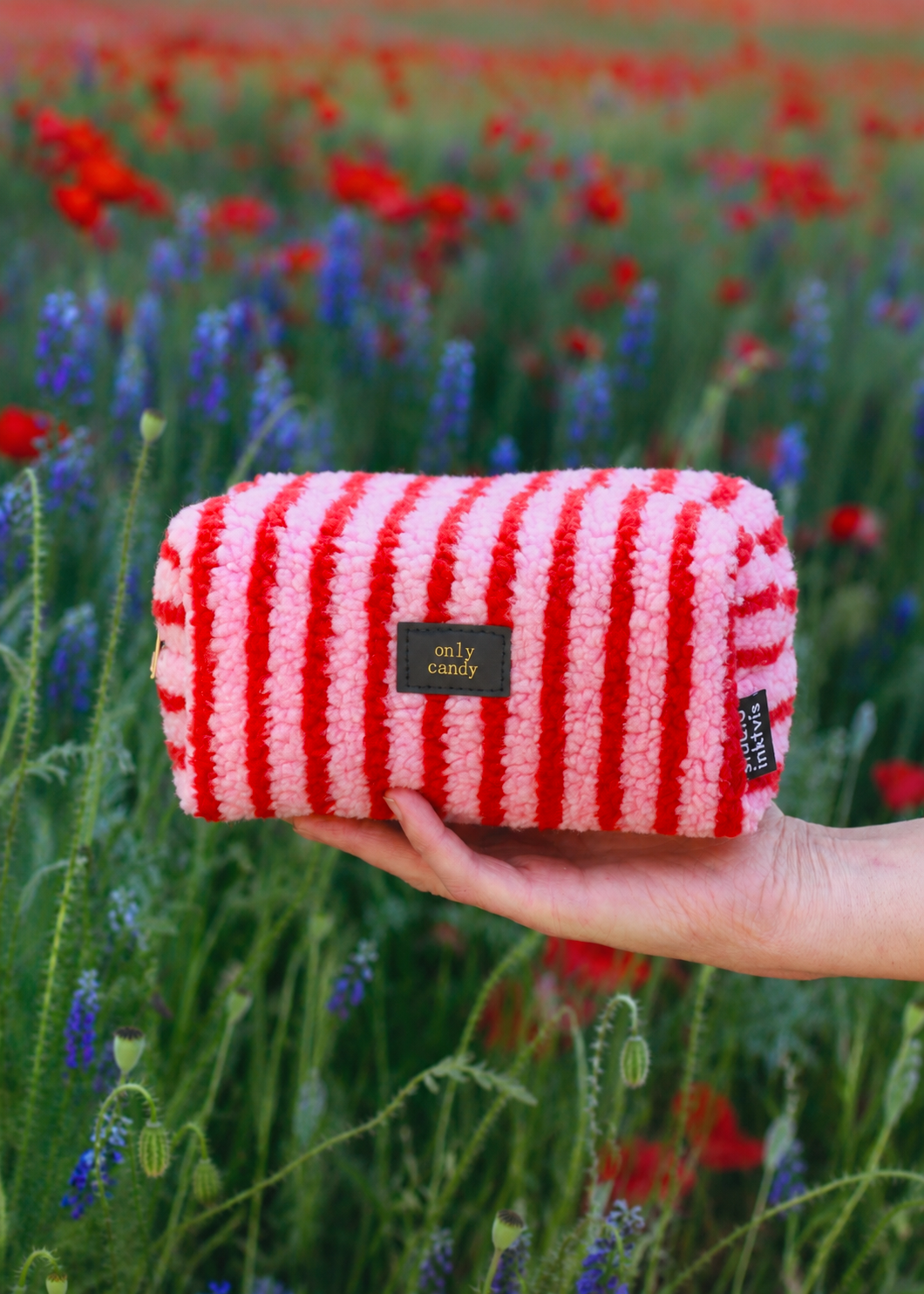 Roze en rood gestreept teddy tasje met Only Candy label in een bloemenveld
