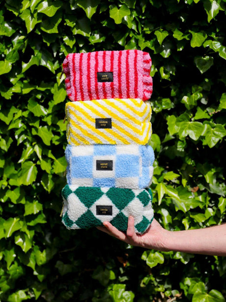Stapel van vier teddy make-up tasjes met patronen, waaronder het geel-wit gestreepte Random Crap tasje.