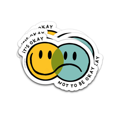 Vaatwasbestendige sticker met overlappende gele blije en blauwe verdrietige smiley en de tekst It's Okay Not To Be Okay.