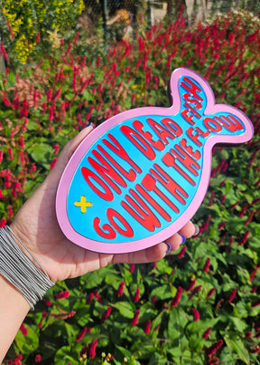 Kleurrijke visvormige wandspiegel van acryl met de tekst Only dead fish go with the flow in roze, blauw, rood en geel.
